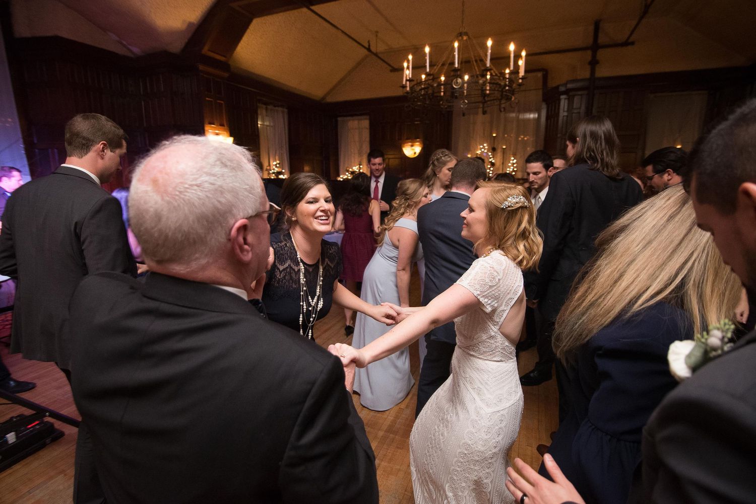 Guests dancing and celebrating at an elegant wedding reception in a warmly lit ballroom.