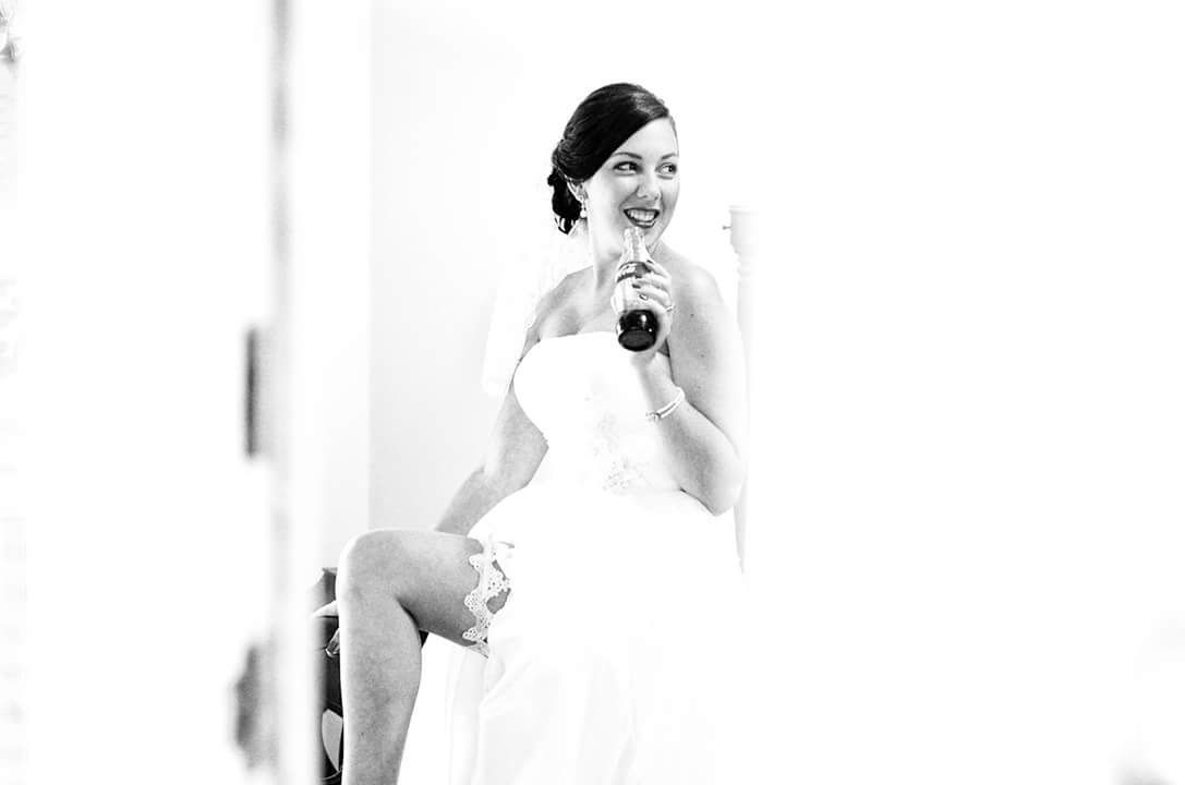 Bride in strapless white gown laughing joyfully in black and white wedding preparation portrait.