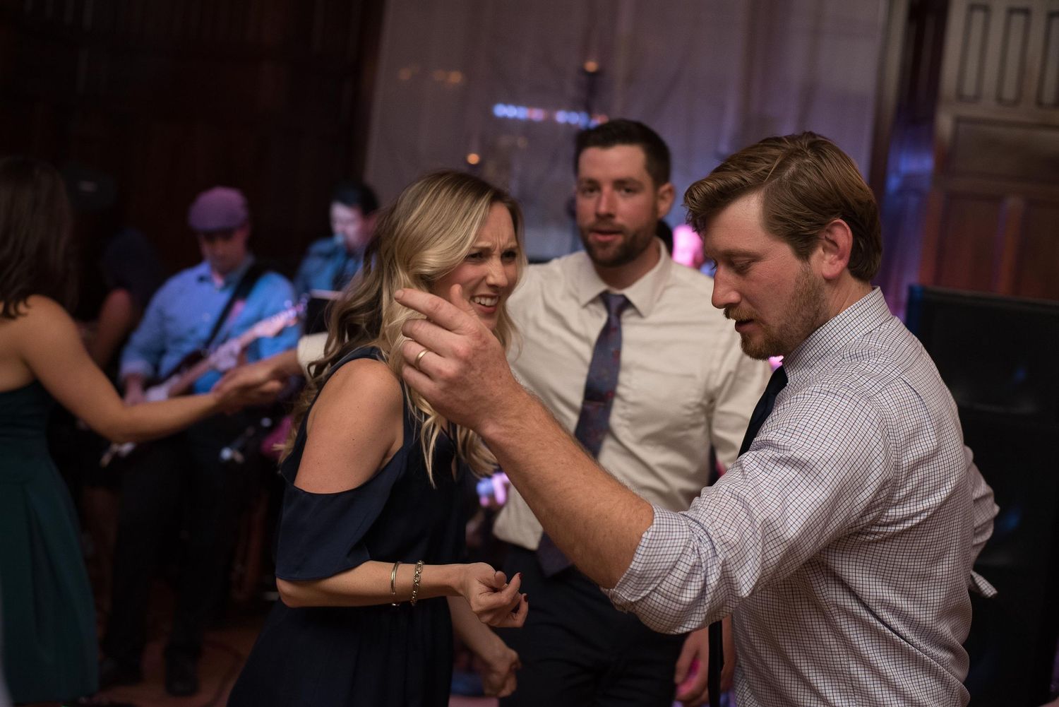 Couple dancing closely at a wedding reception with a live band performing in the background.