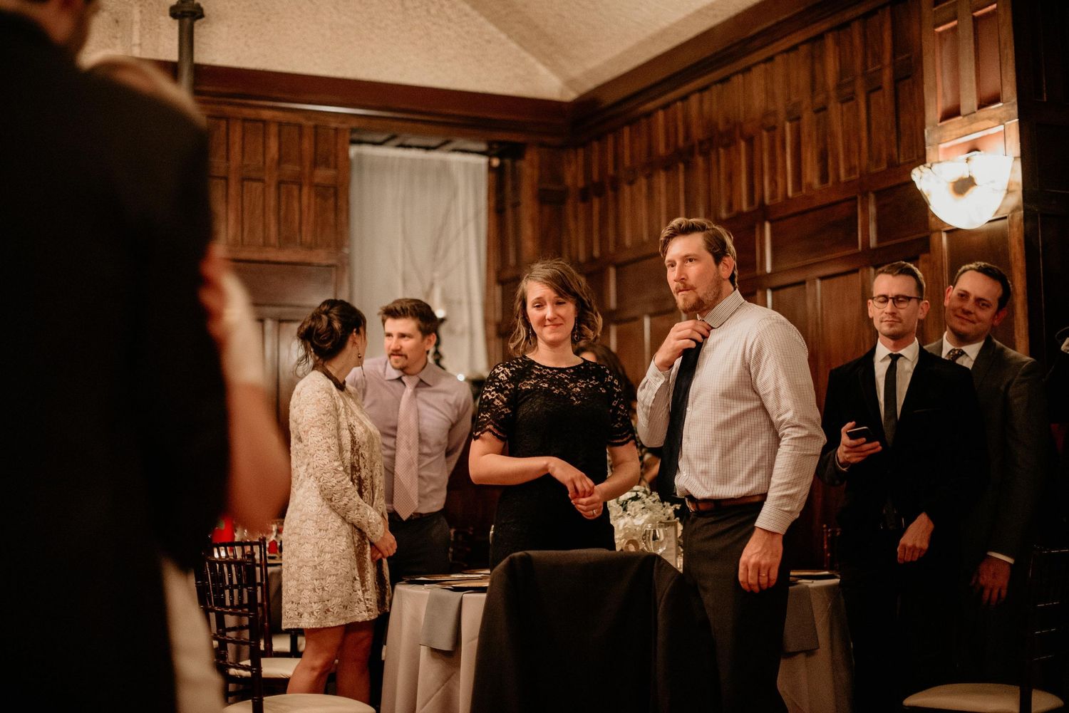 Guests mingling at an elegant wood-paneled reception hall during a formal event or wedding celebration.