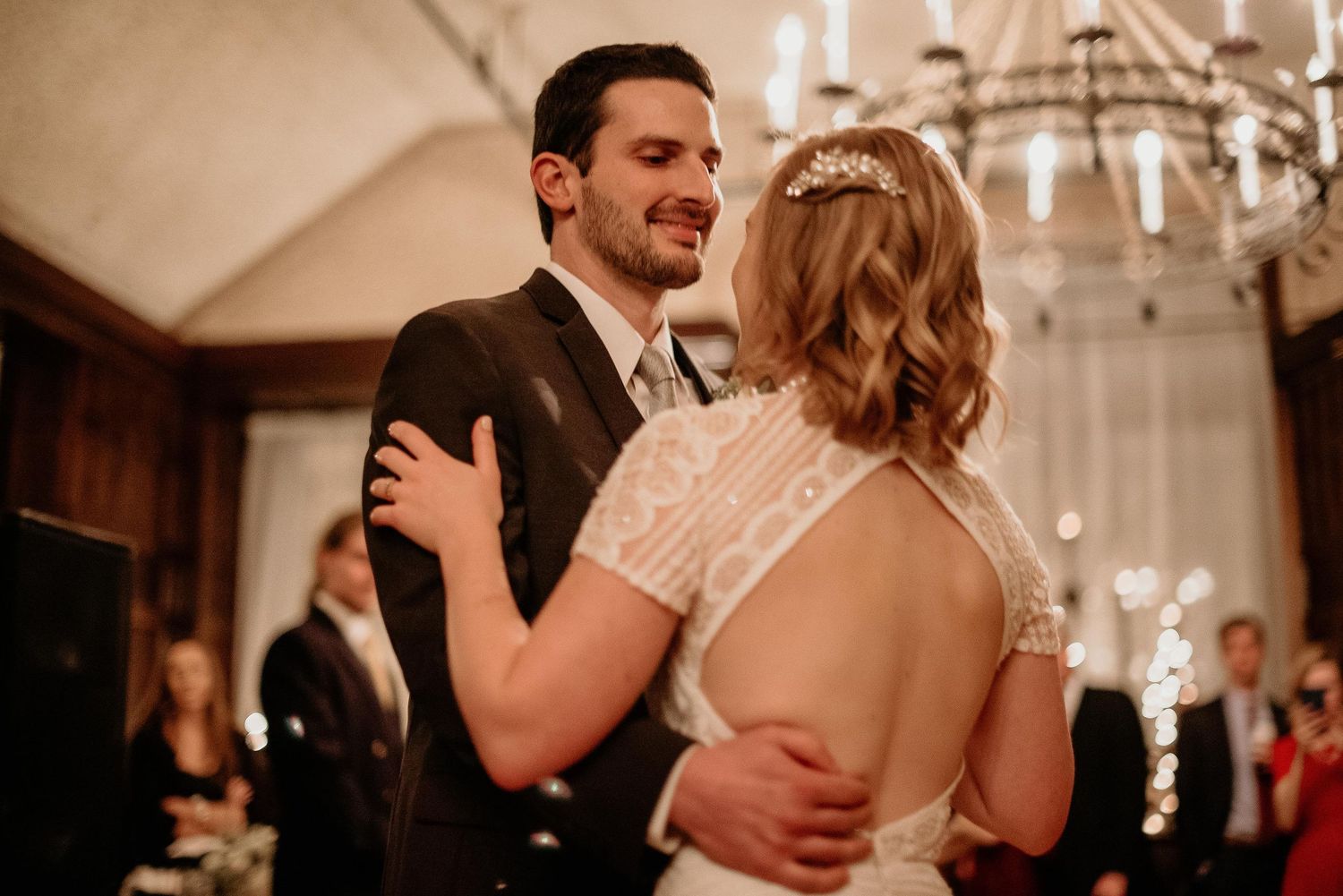 Bride and groom share their first dance under a chandelier at an elegant wedding reception.