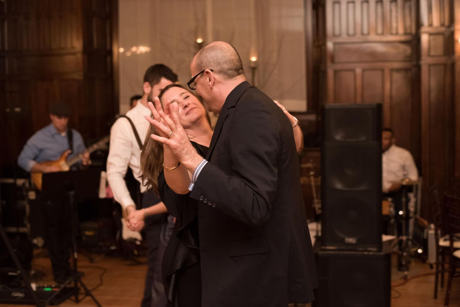Couple sharing a romantic dance at a wedding reception with a live band performing in the background.