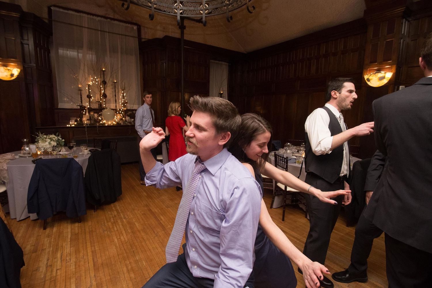 Guests dancing and socializing at an elegant wedding reception in a warmly lit ballroom.