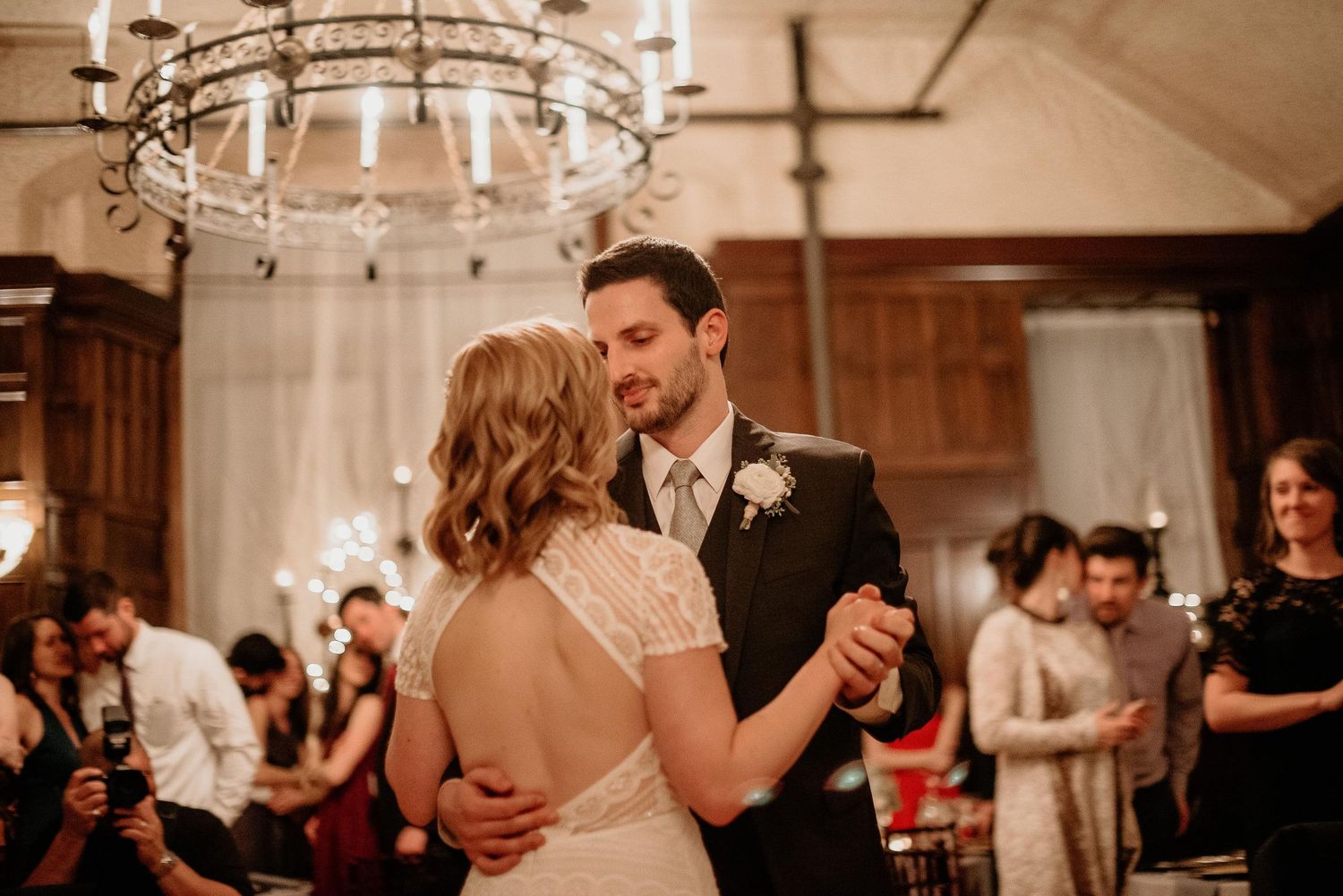 Bride and groom share their first dance under a chandelier at an elegant wedding reception.
