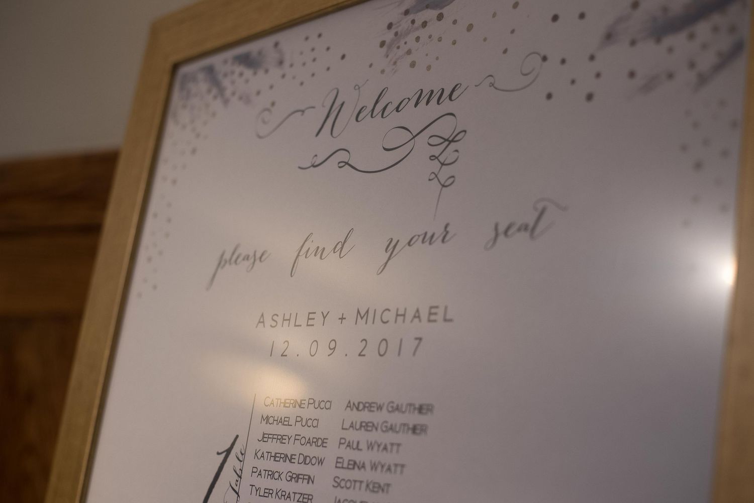 Elegant wedding seating chart sign welcoming guests for Ashley and Michael, dated 12.09.2017, in a wooden frame.