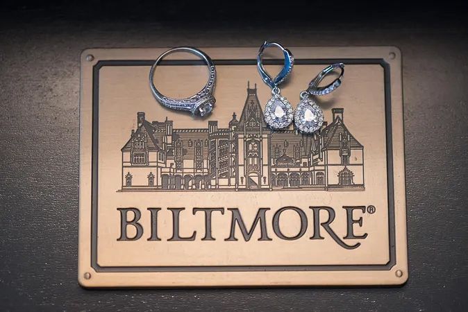 Diamond wedding rings and earrings displayed on a bronze Biltmore Estate engraved sign.