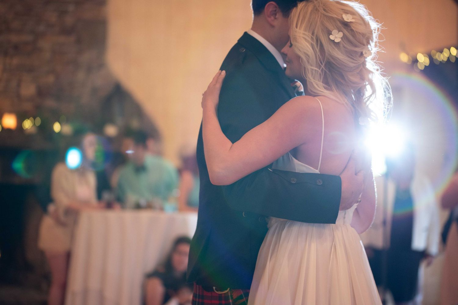 Bride and groom sharing their first dance at a romantic wedding reception with warm glowing lights.