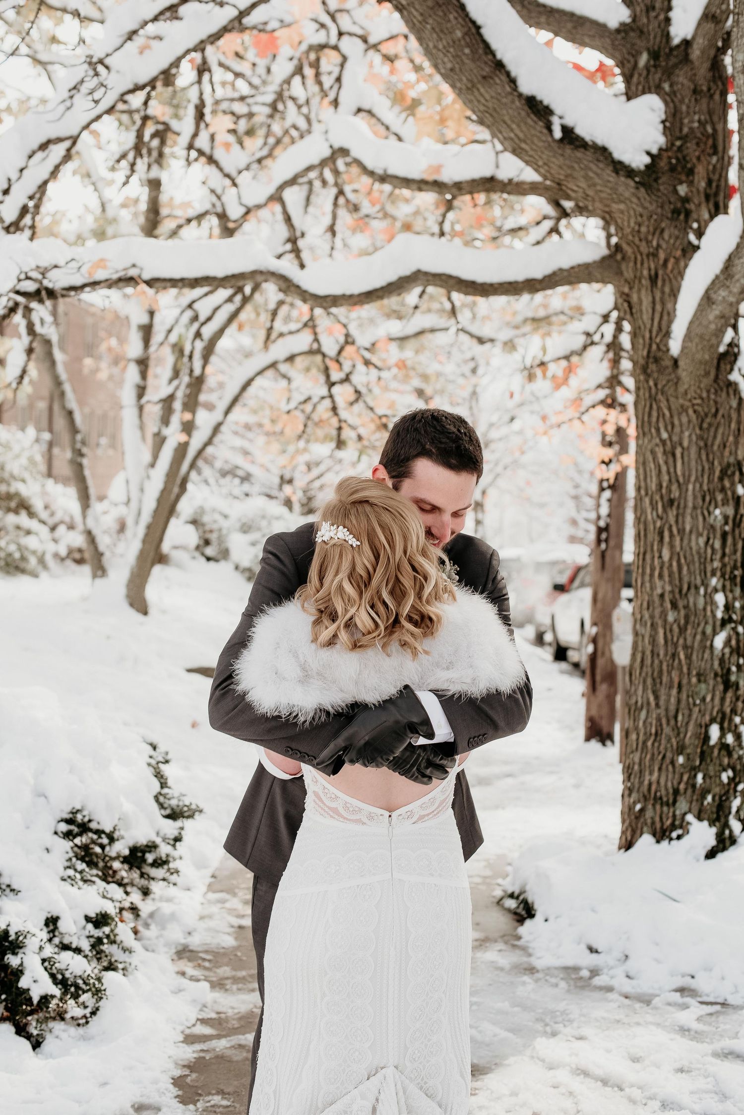 Bride and groom embrace in a snowy winter wonderland, with snow-covered trees and a romantic outdoor setting.