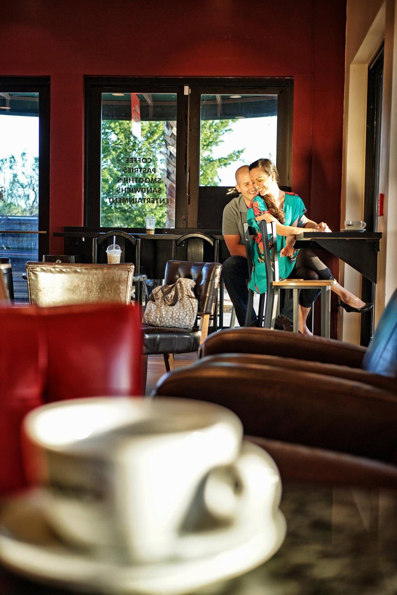 Happy couple sharing a laugh together at a cozy red-walled coffee shop cafe.
