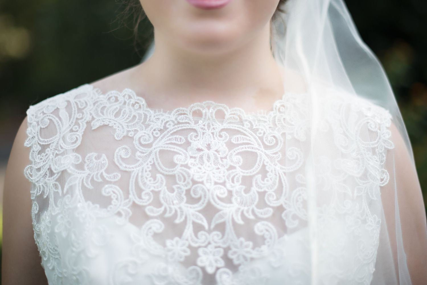 Close-up of bride wearing intricate lace bodice wedding gown with delicate embroidery detailing.