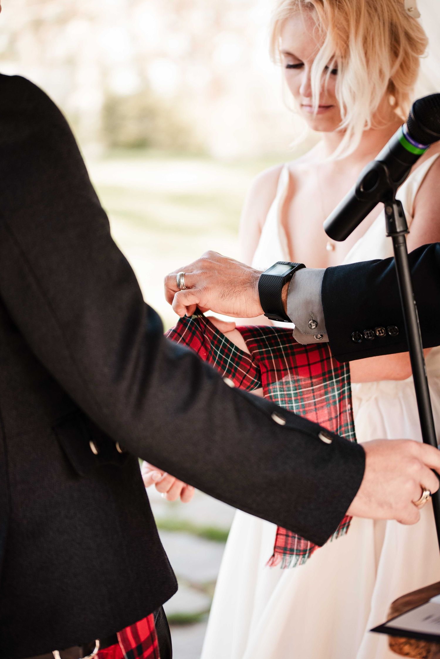 Bride and groom exchange rings during Scottish wedding ceremony, groom wearing traditional red tartan kilt.