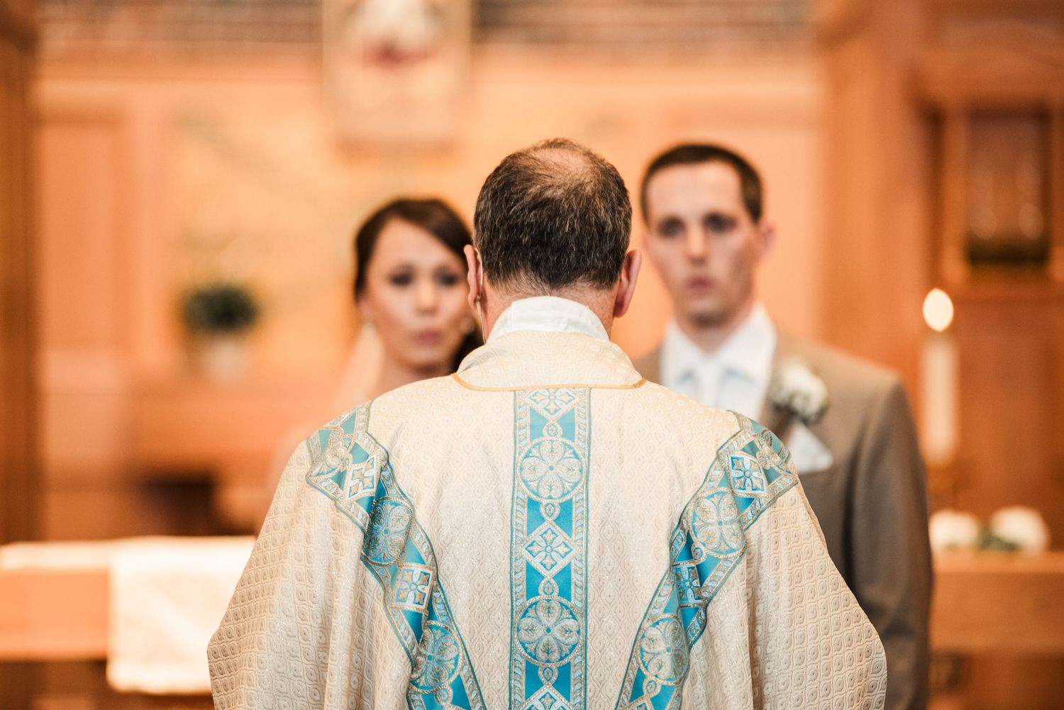 A Catholic priest in ornate vestments officiates a wedding ceremony at the altar.