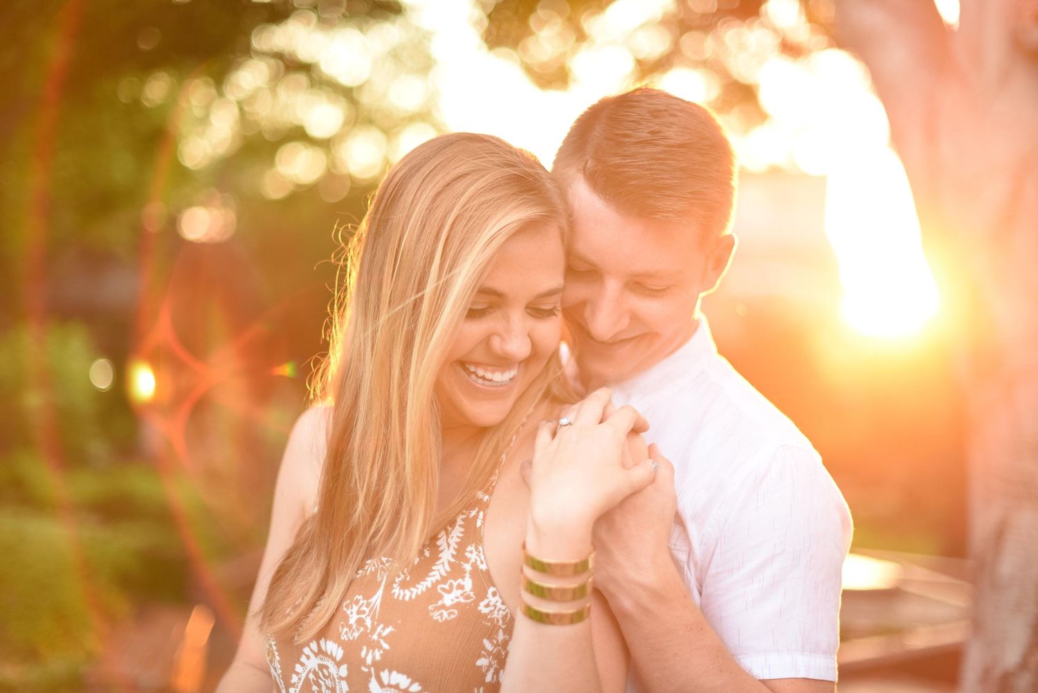 Couple sharing a joyful embrace bathed in warm golden sunset light outdoors.