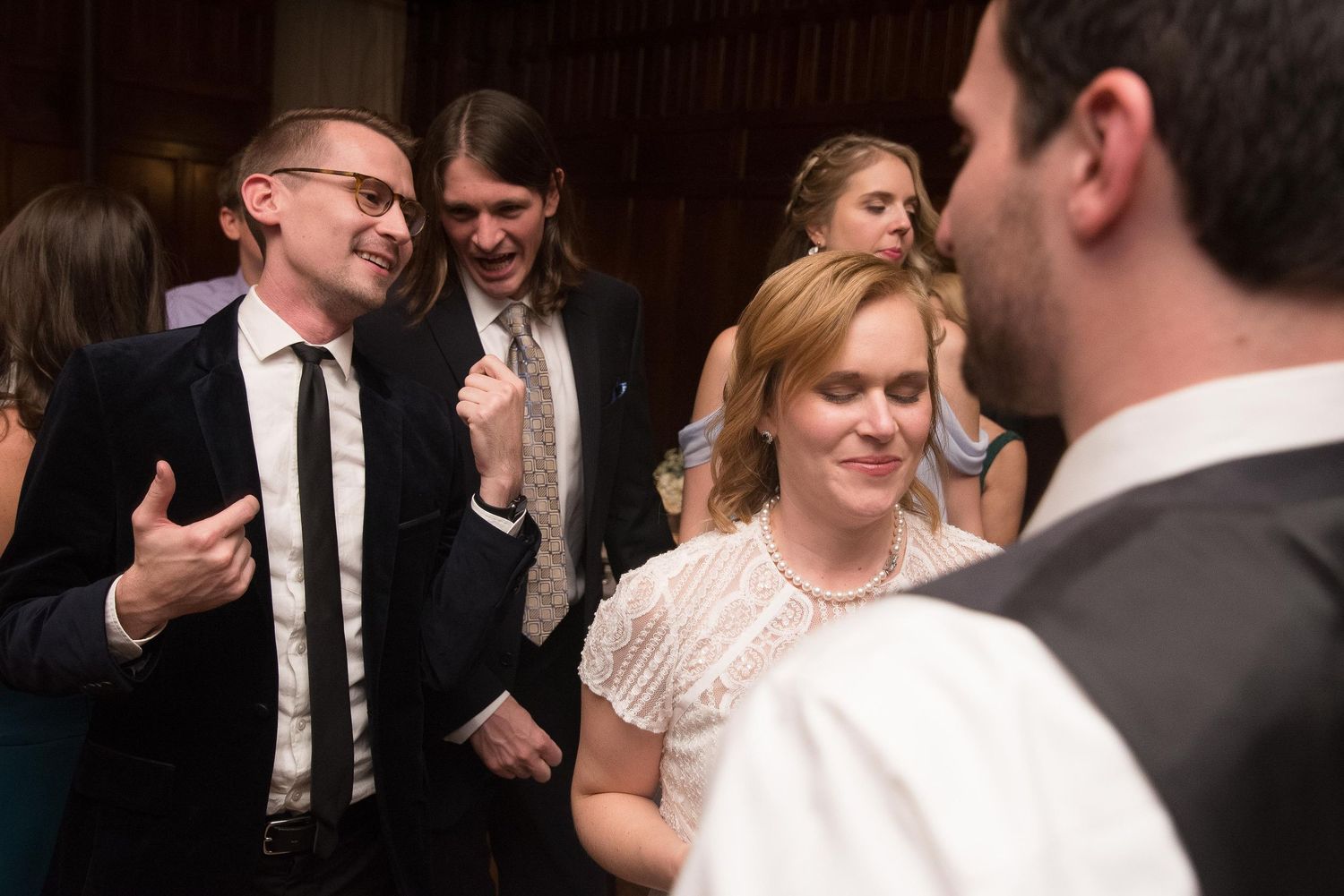 Guests socializing and laughing at a wedding reception in a formal venue setting.