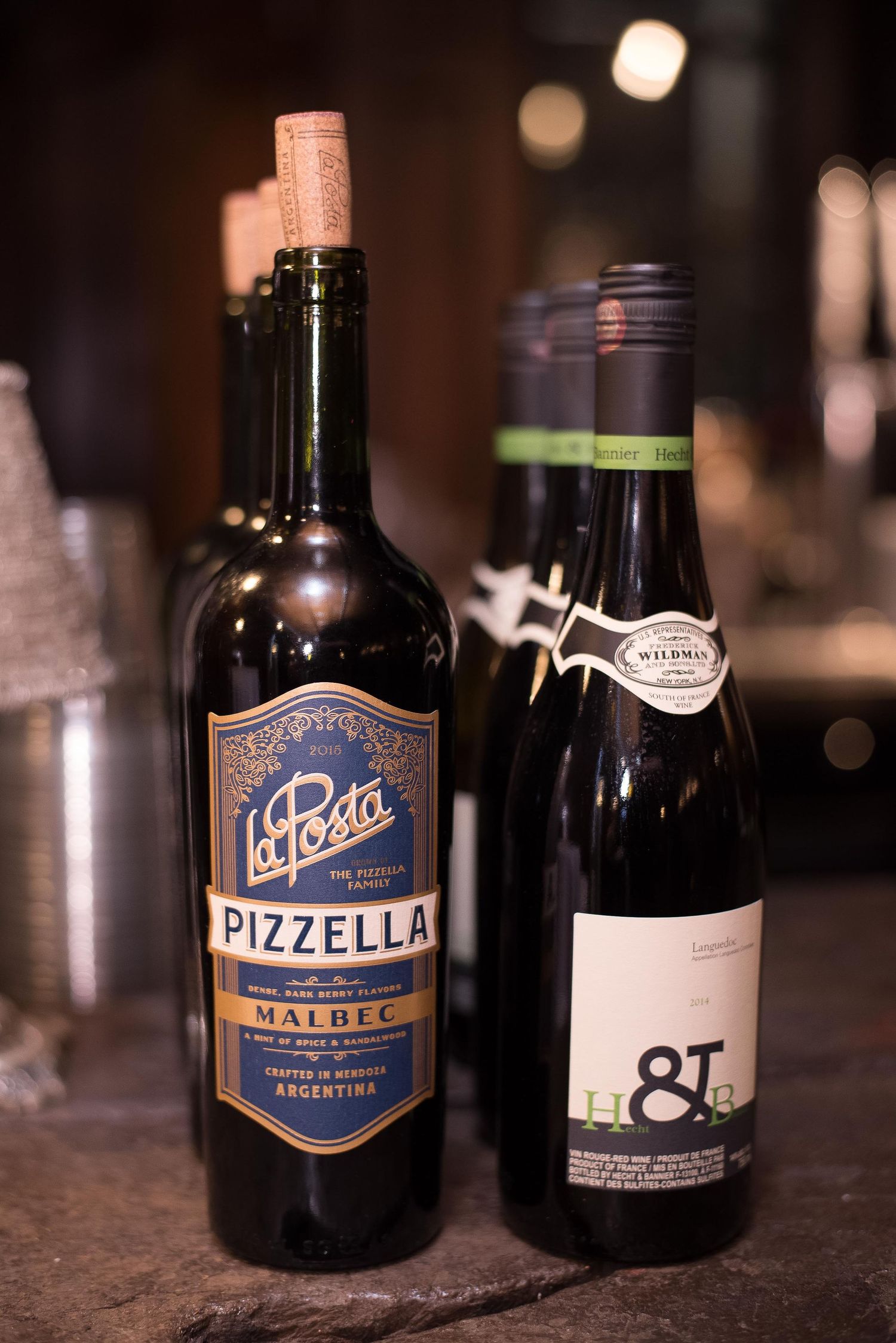 Two wine bottles including La Posta Pizzella Malbec from Argentina displayed on a dark surface.