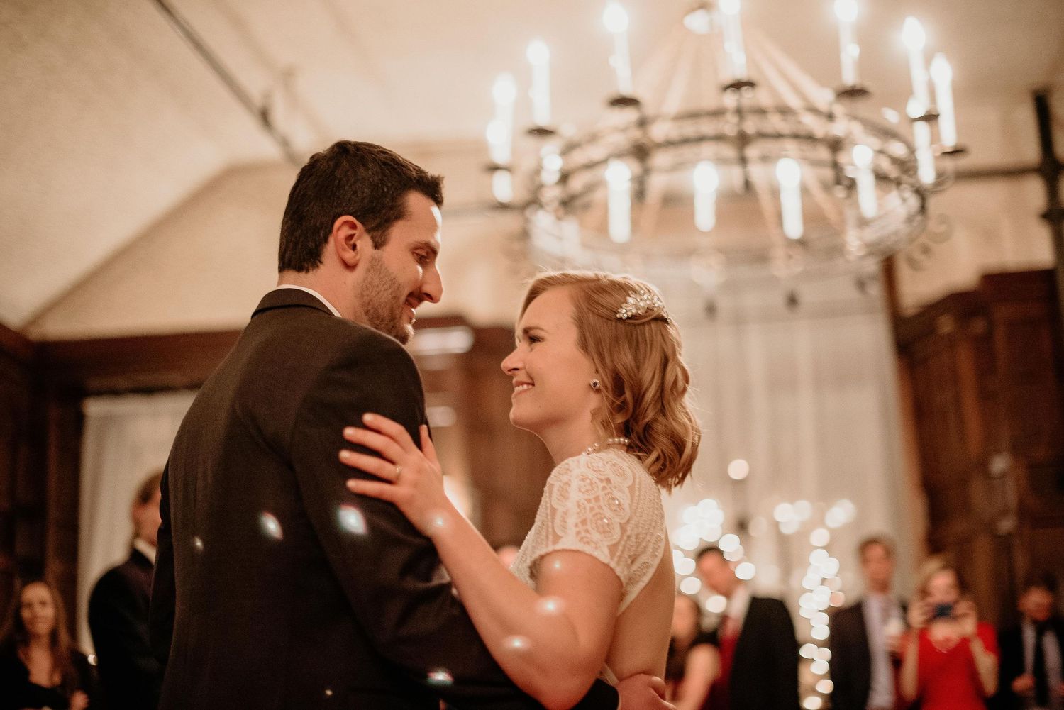Bride and groom share first dance under elegant chandelier at romantic wedding reception.