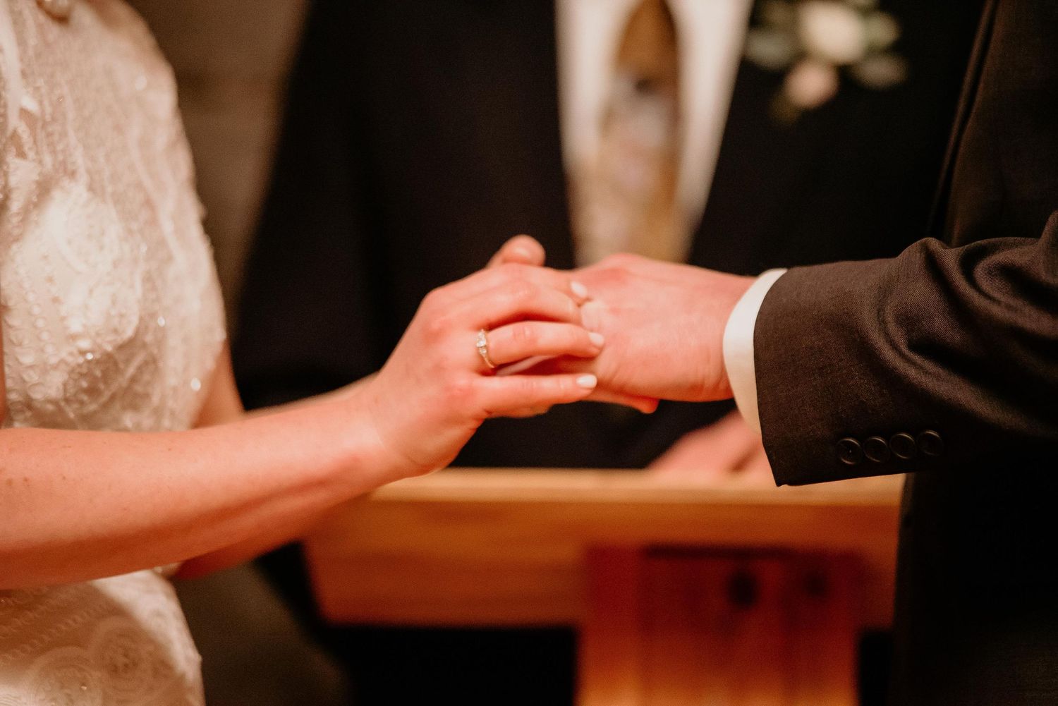 Close-up of bride placing wedding ring on grooms hand during romantic wedding ceremony ring exchange.