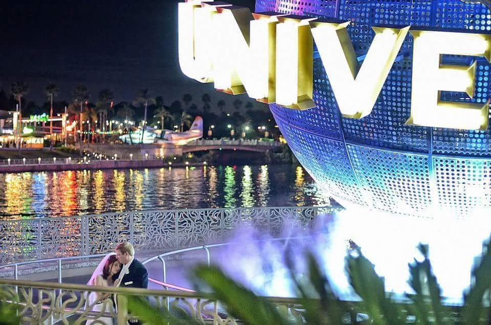 Couple shares romantic moment near illuminated Universal Studios globe at night.