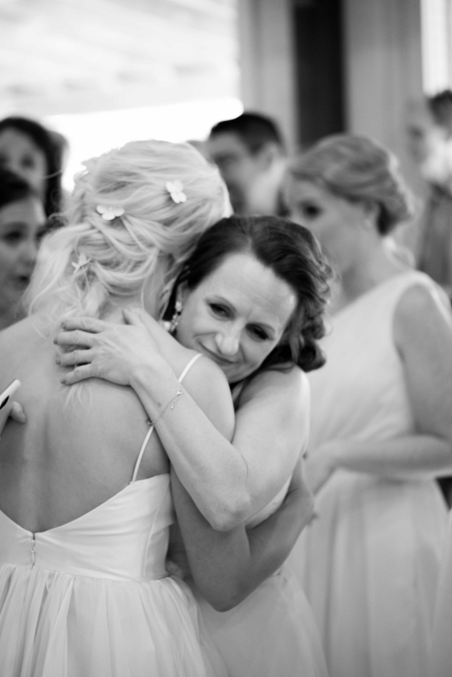Two bridesmaids share a warm embrace at a wedding celebration in black and white photography.