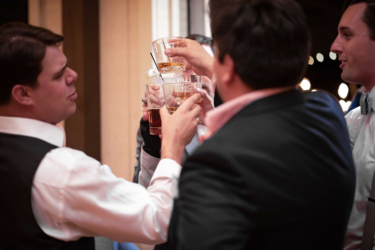 Men in formal attire toasting with drinks at a celebration event.