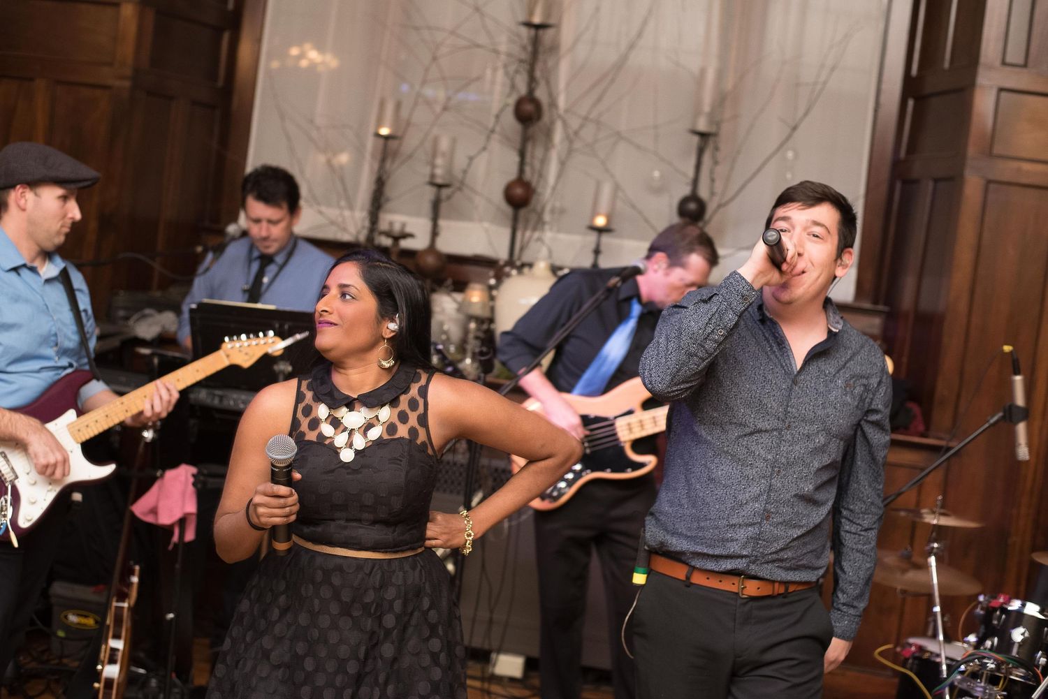 Live band performing at an indoor event, featuring a female vocalist and guitarist in elegant venue.