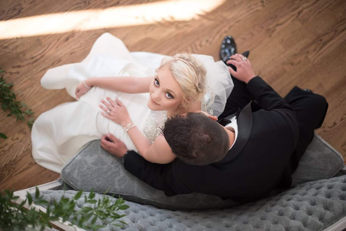 Bride and groom sharing a romantic moment lying on the floor, viewed from above.