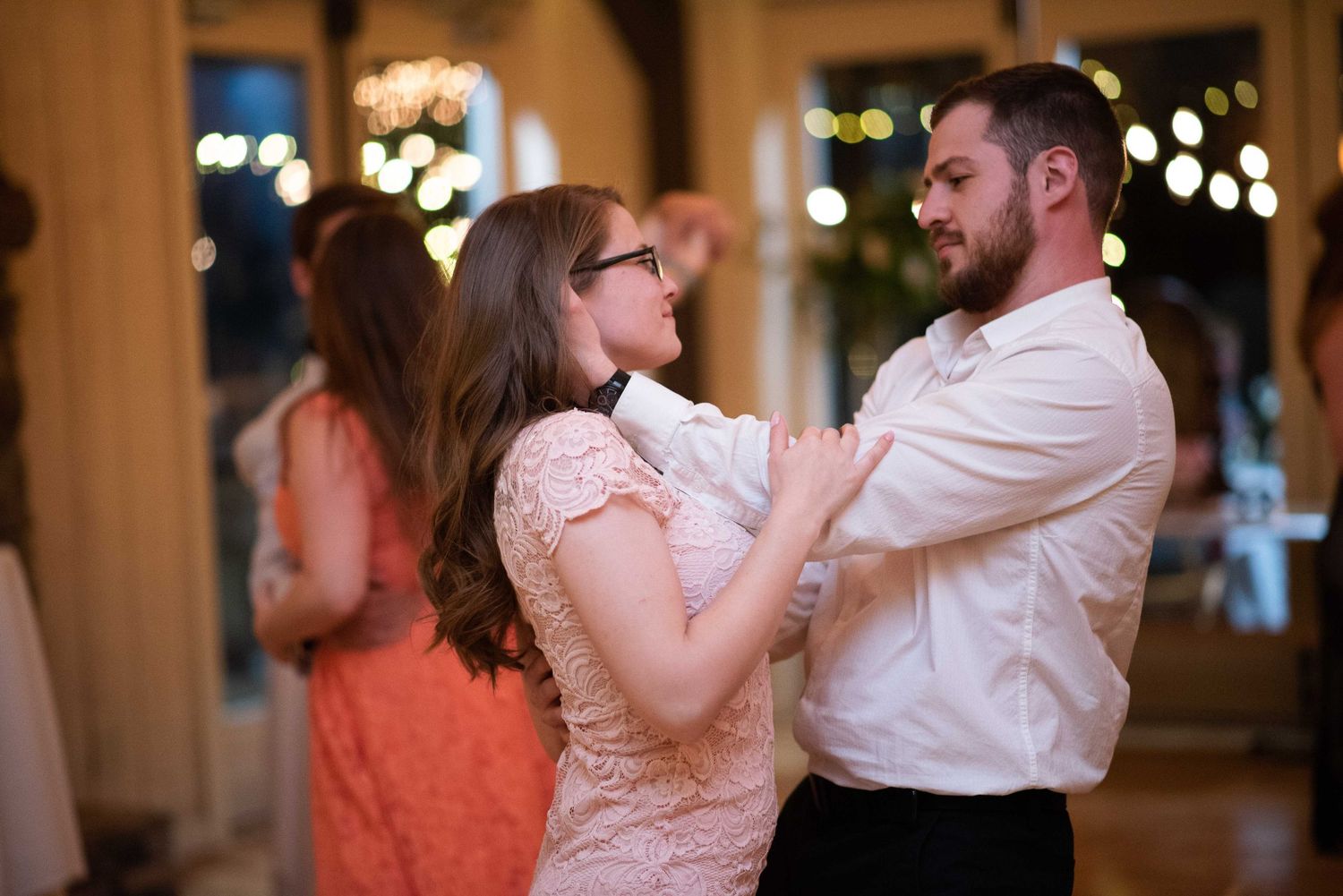 Couple sharing a romantic dance at a wedding reception with bokeh lights in the background.