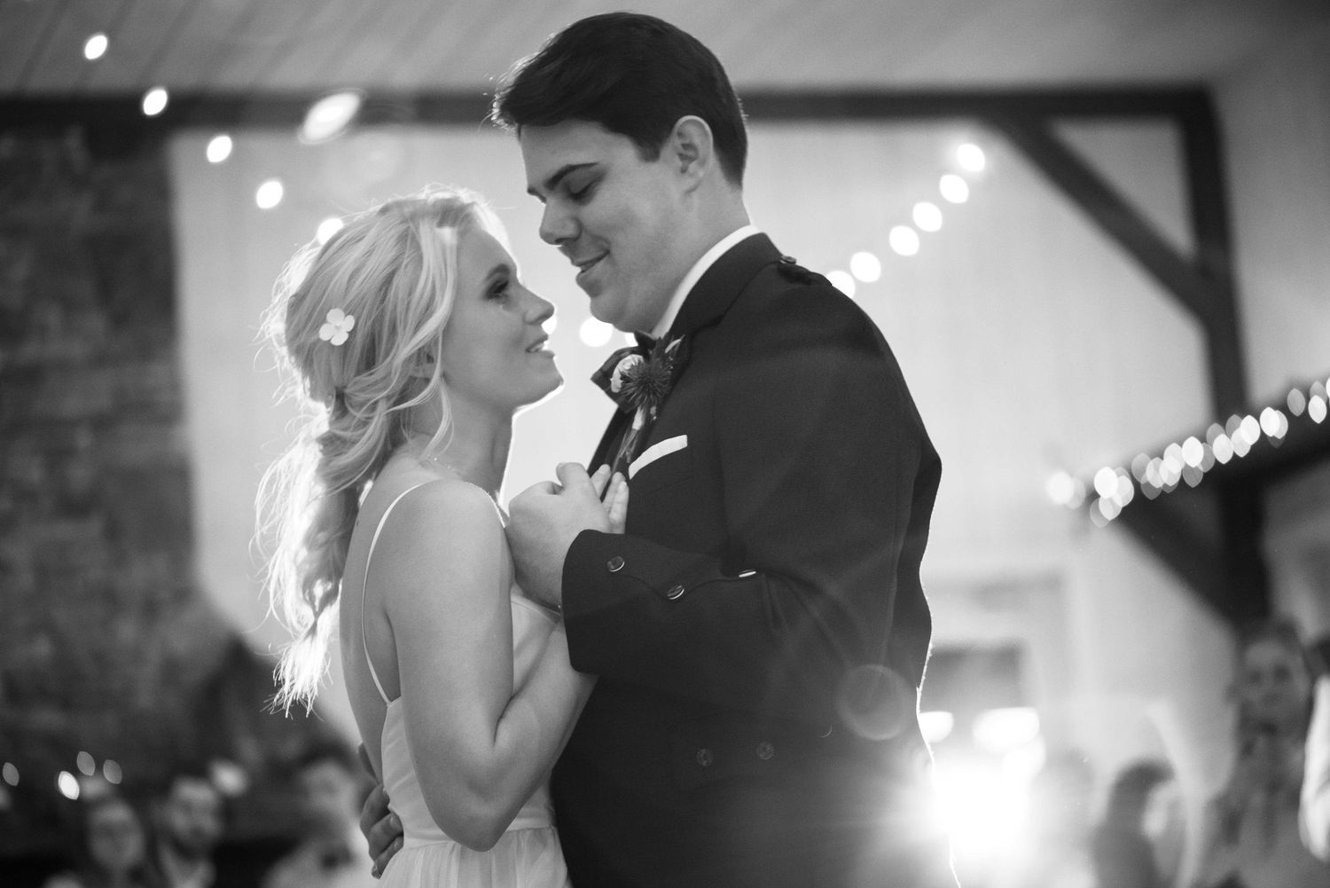 Black and white photo of a bride and groom sharing their first dance at a romantic wedding reception.