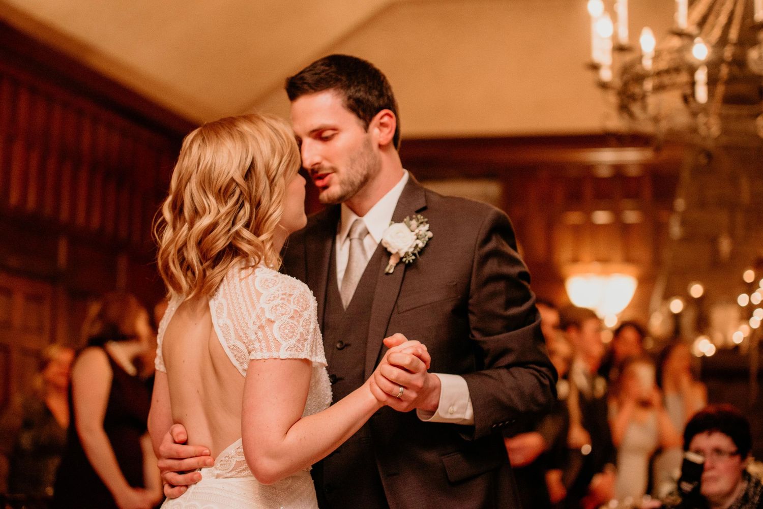 Bride and groom share their first dance in an elegantly lit wedding reception hall.