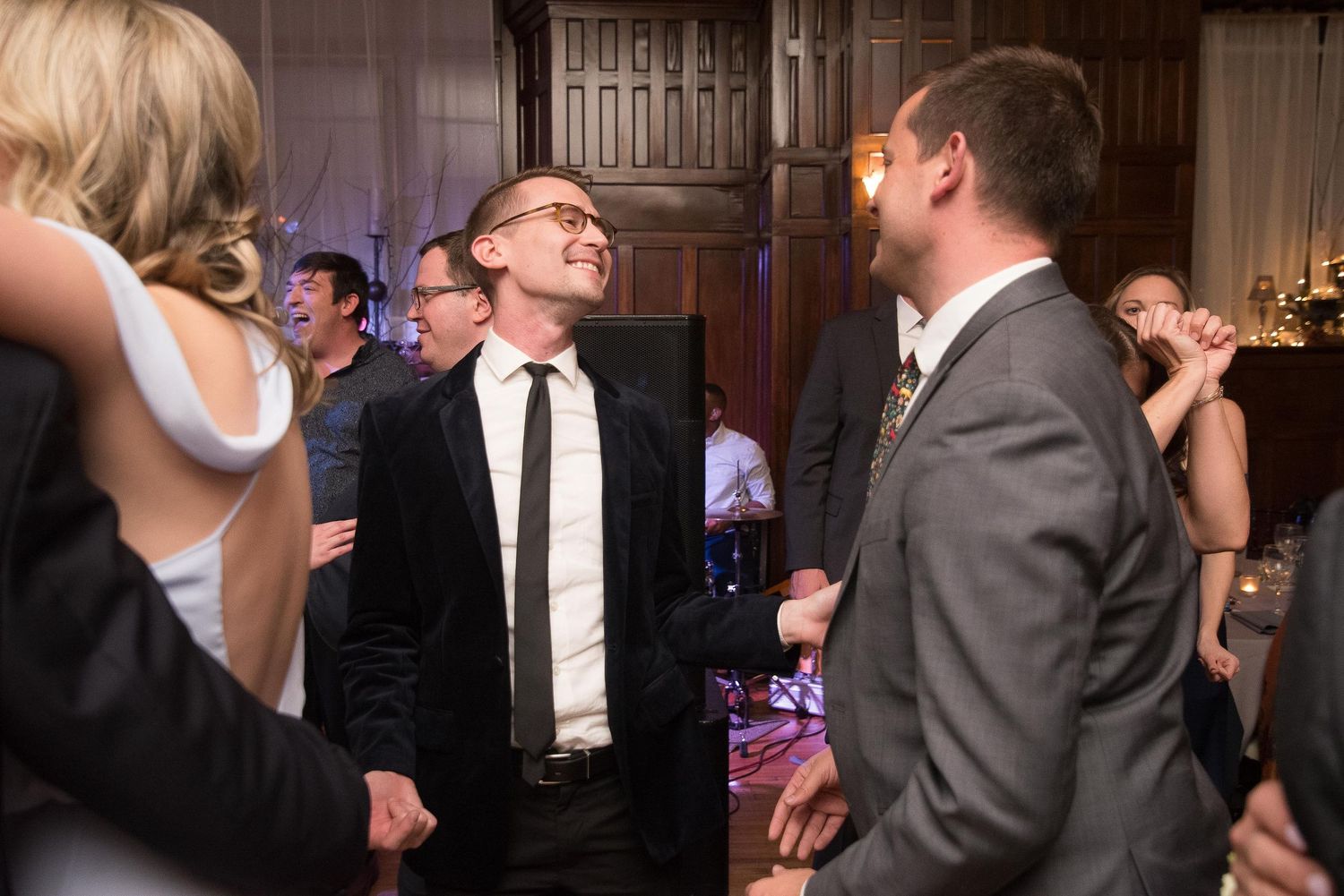 Guests in formal attire socializing and laughing at an elegant indoor event or wedding reception.