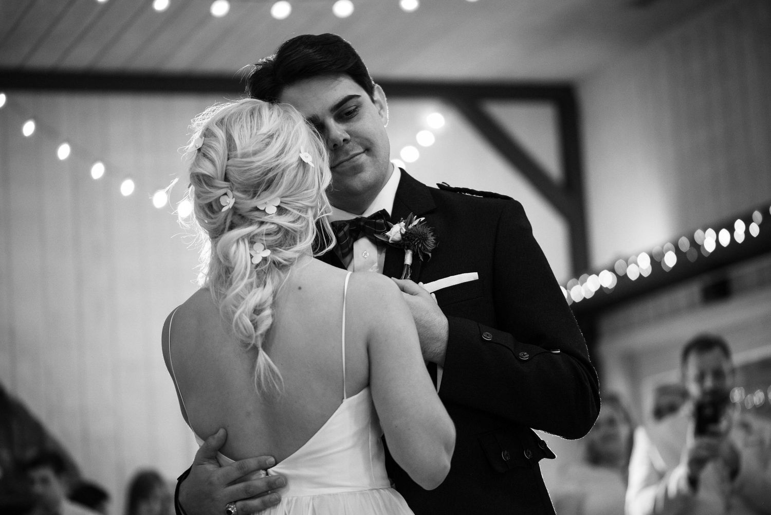 Black and white photo of a bride and groom sharing their first dance at a romantic wedding reception.