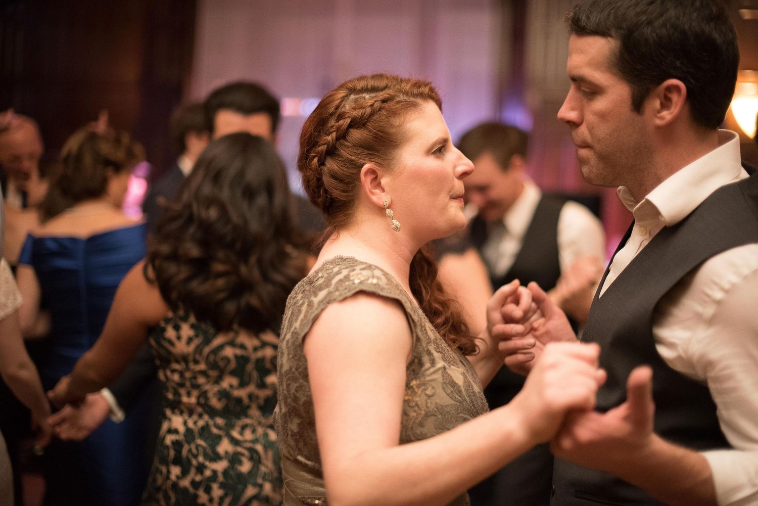 Couple dancing closely together at a formal event, woman in elegant dress with braided updo, man in suit.