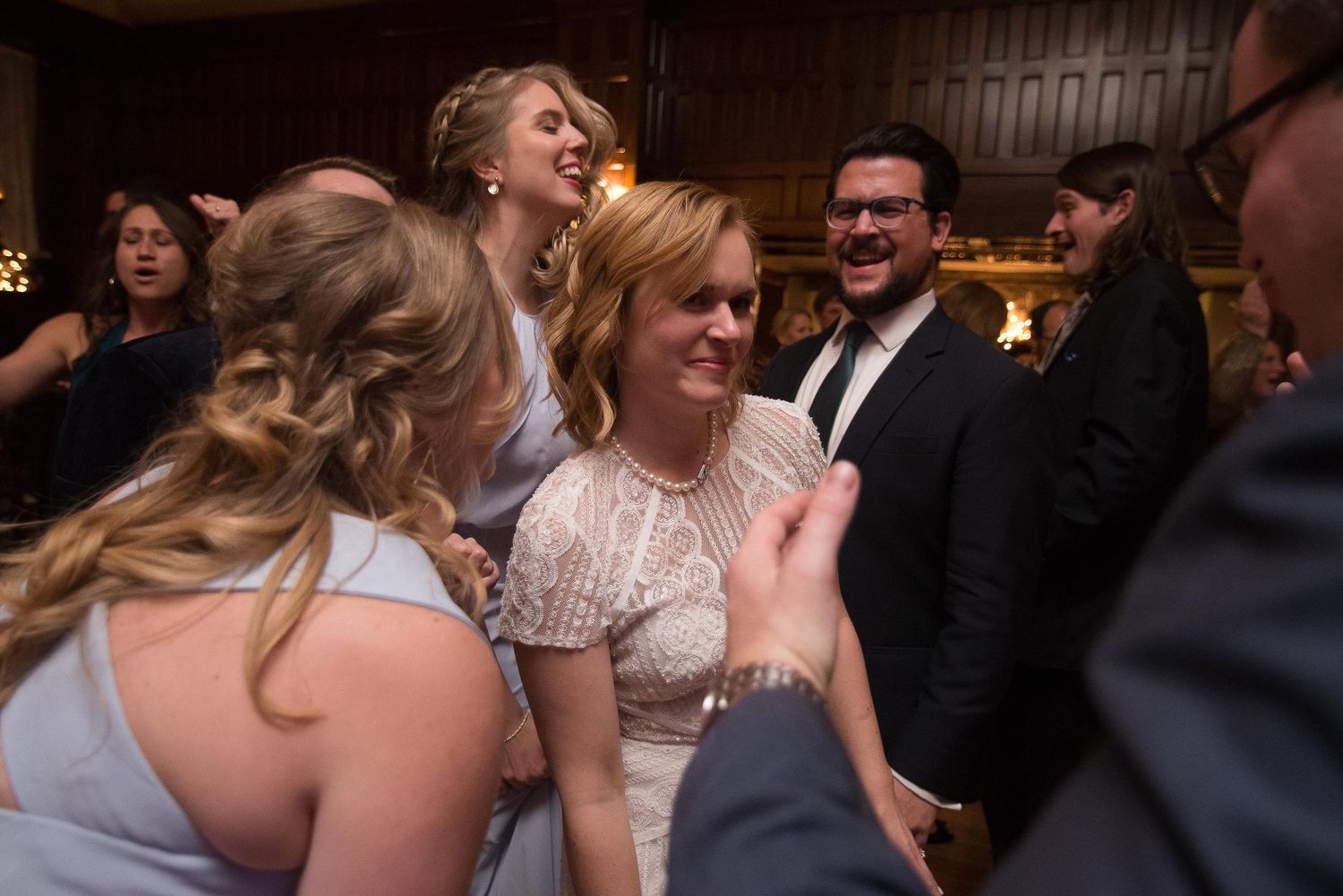 Joyful wedding reception guests laughing and dancing together in elegant venue.