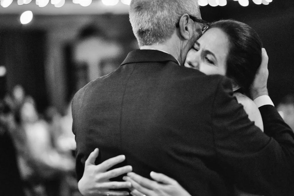 Bride and groom sharing tender embrace on wedding dance floor in black and white photo.