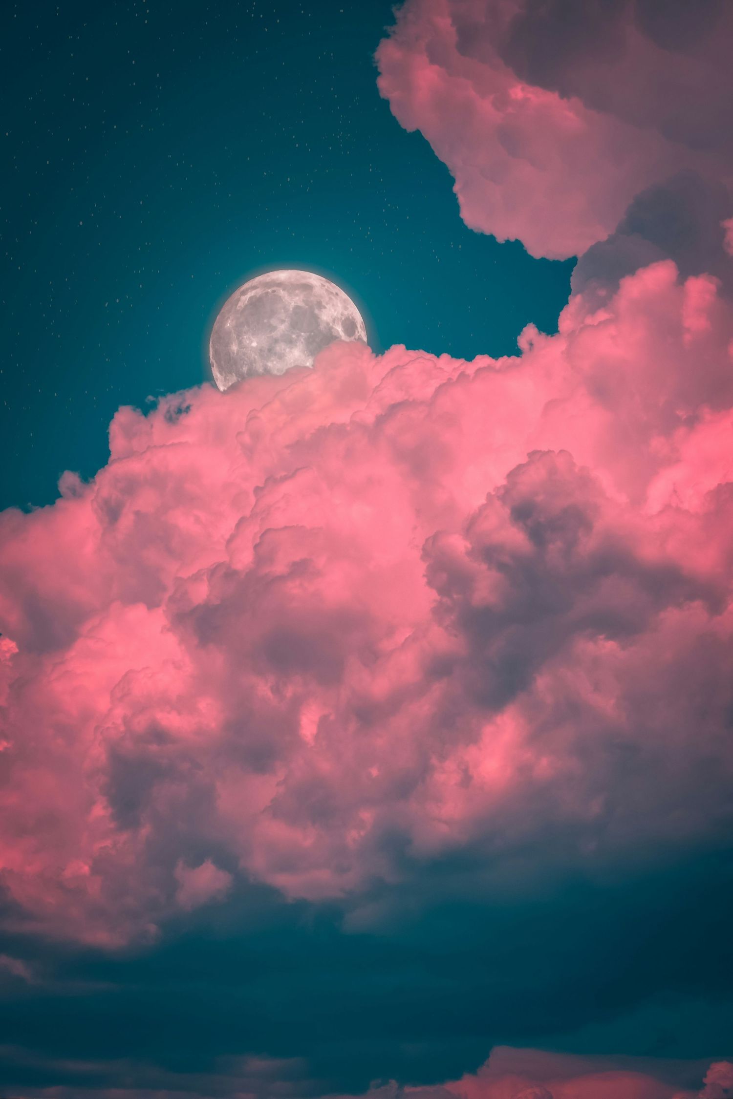 Full moon rising behind dramatic pink and magenta cumulus clouds against deep teal starry night sky.