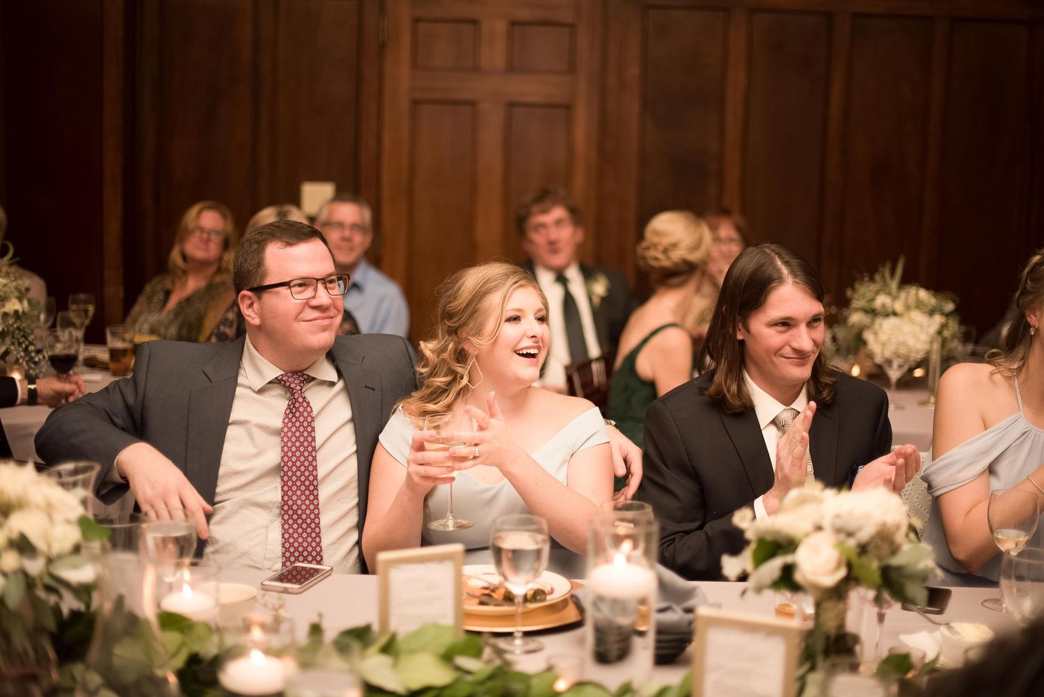 Wedding guests laughing and celebrating at elegant reception dinner table.