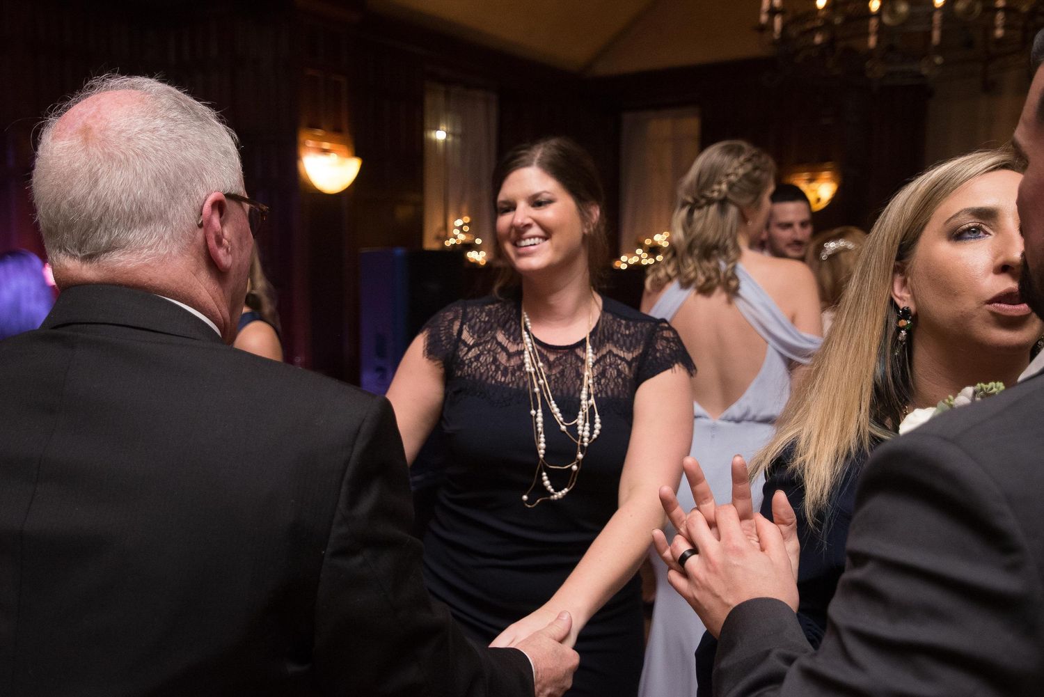 Guests smiling and dancing at an elegant formal event in a warmly lit ballroom.