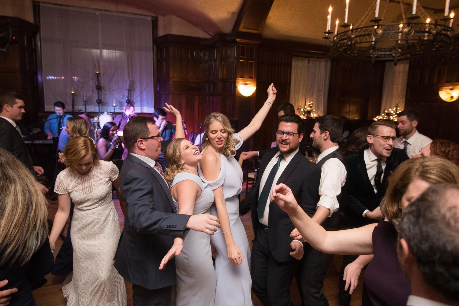 Guests dancing joyfully at an elegant wedding reception in a candlelit ballroom.