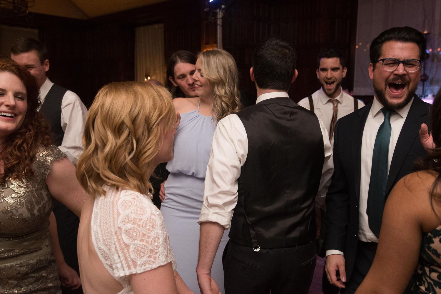 Guests dancing and celebrating at a lively wedding reception party indoors.