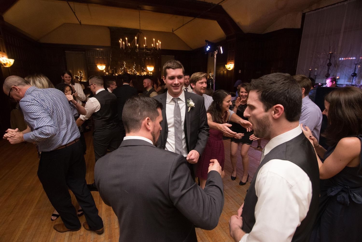 Guests dancing and celebrating at an elegant wedding reception in a warmly lit ballroom.