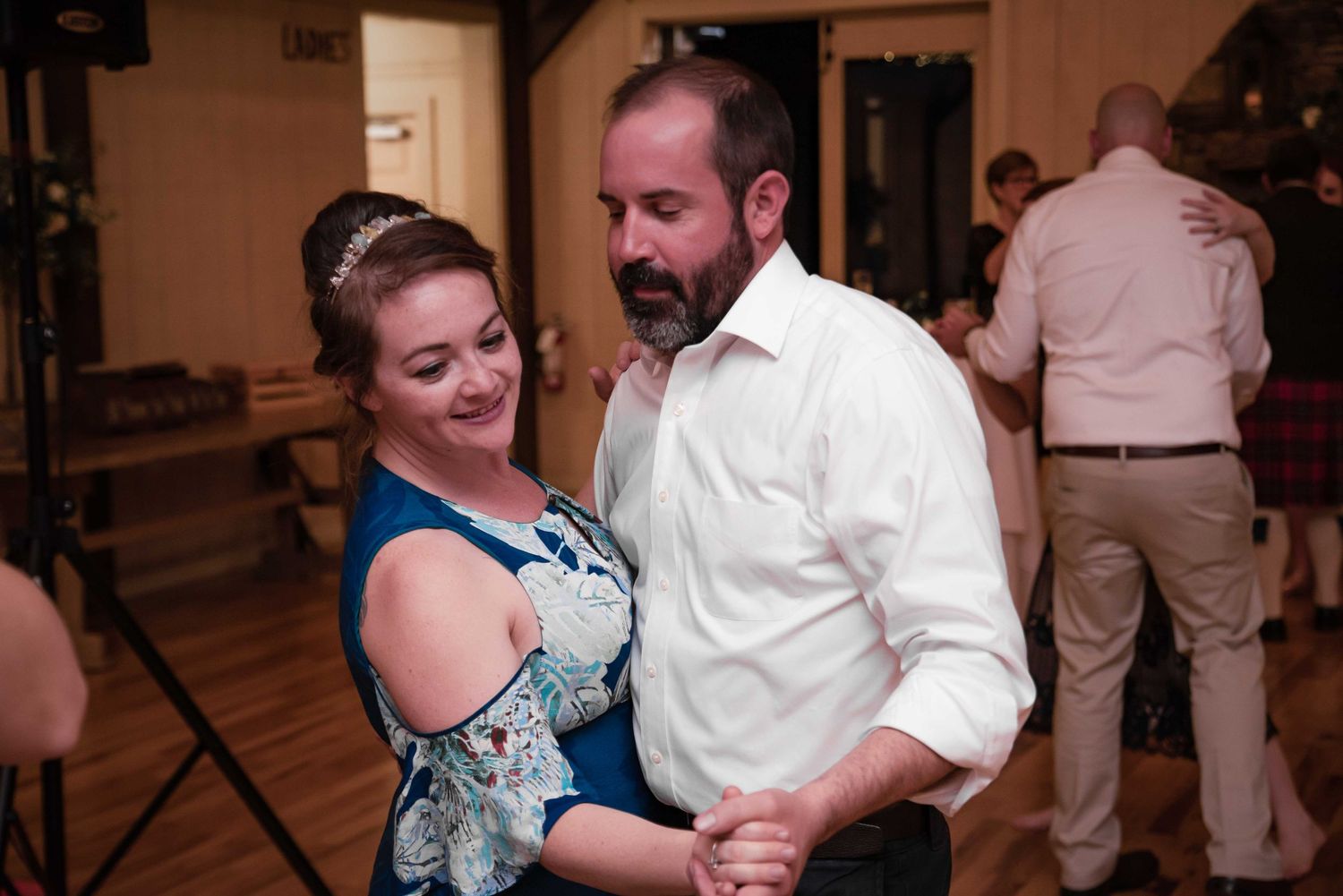 Couple dancing together at a wedding reception in a warmly lit venue.