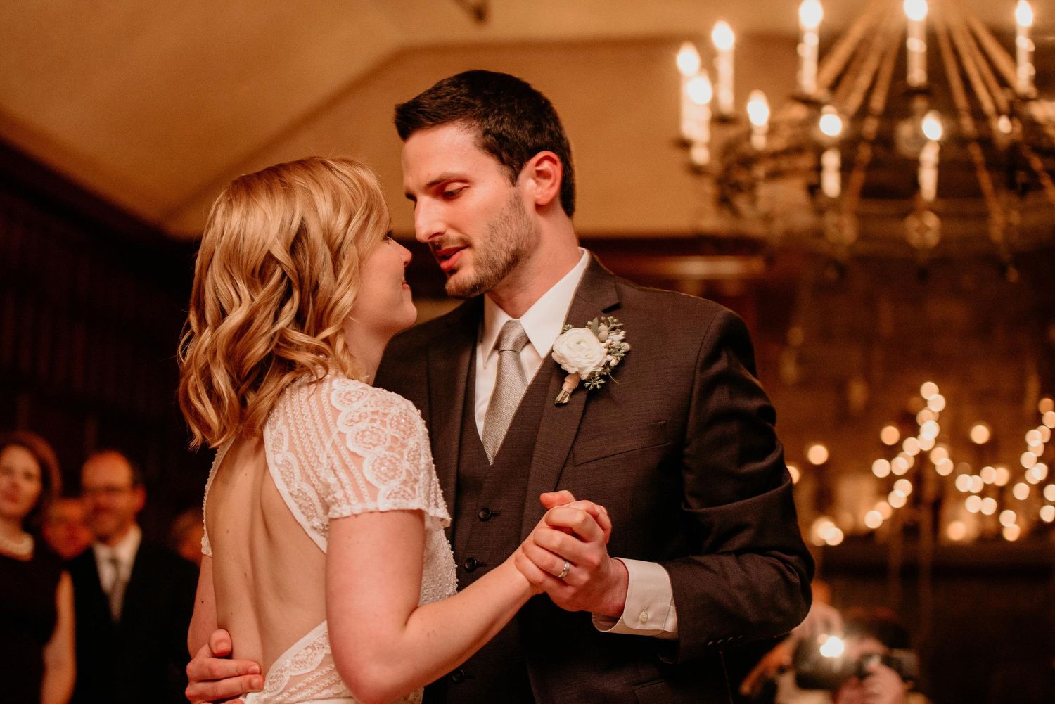 Bride and groom share their first dance under a chandelier at an elegant wedding reception.