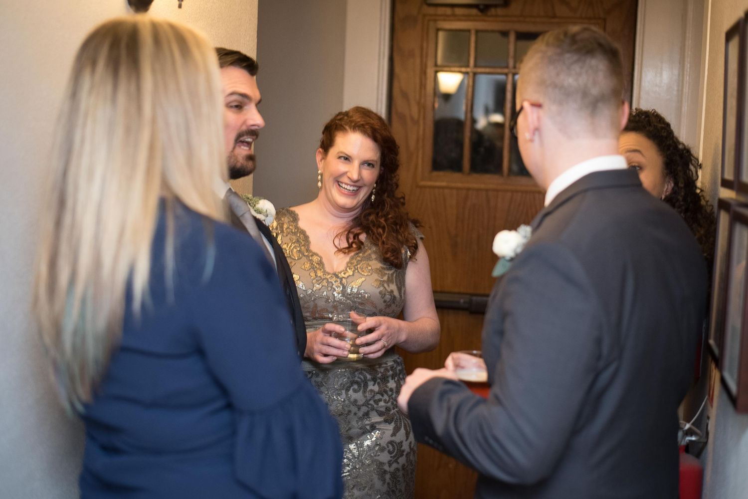 Guests socializing at a wedding reception, smiling and holding drinks in elegant formal attire.