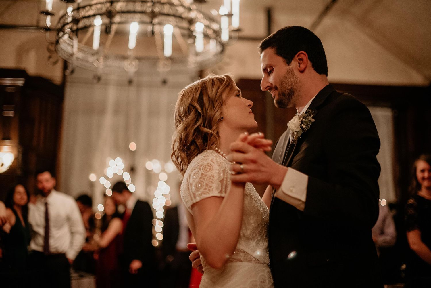 Bride and groom share their first dance under a chandelier at a romantic wedding reception.
