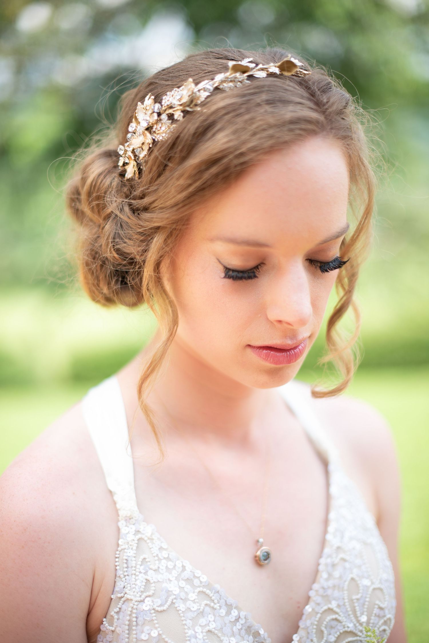 Beautiful bride with an elegant updo adorned with a gold floral crown wearing a lace wedding dress.