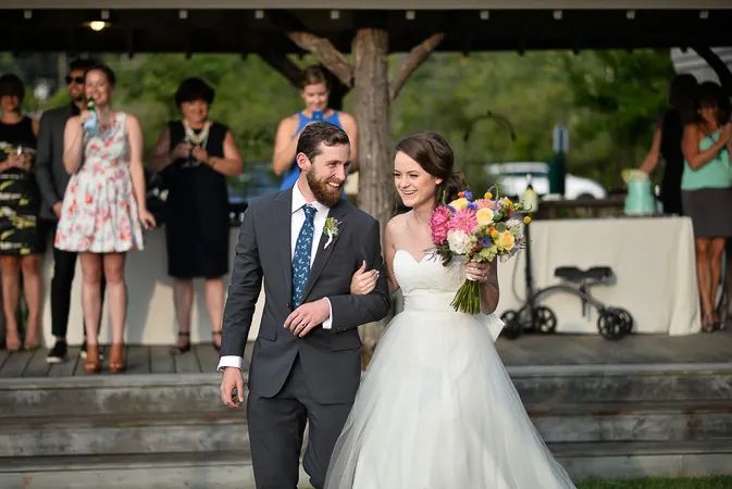 Newlyweds walking down the aisle after ceremony with colorful bridal bouquet.