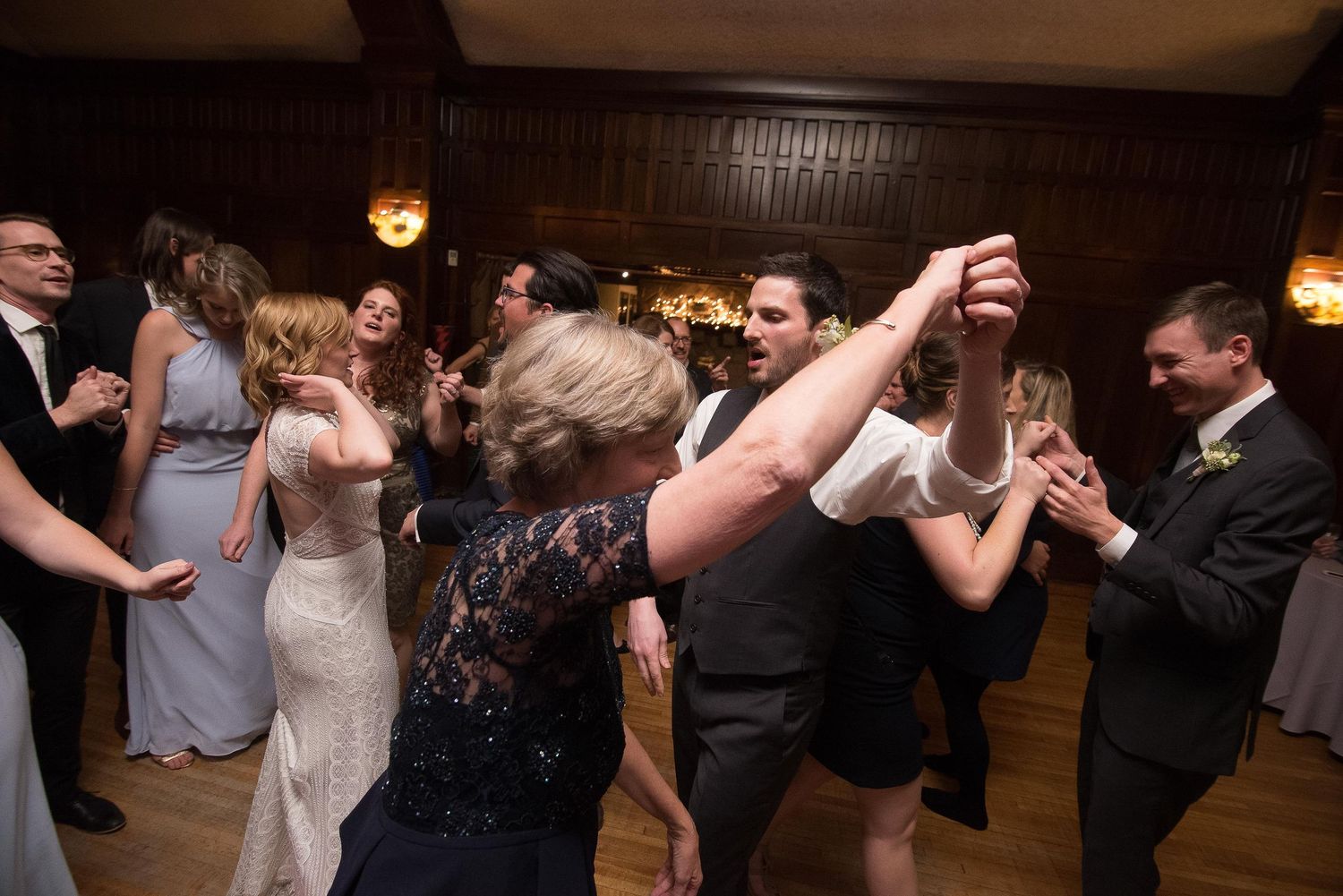 Guests dancing energetically on crowded wedding reception dance floor in elegant venue.