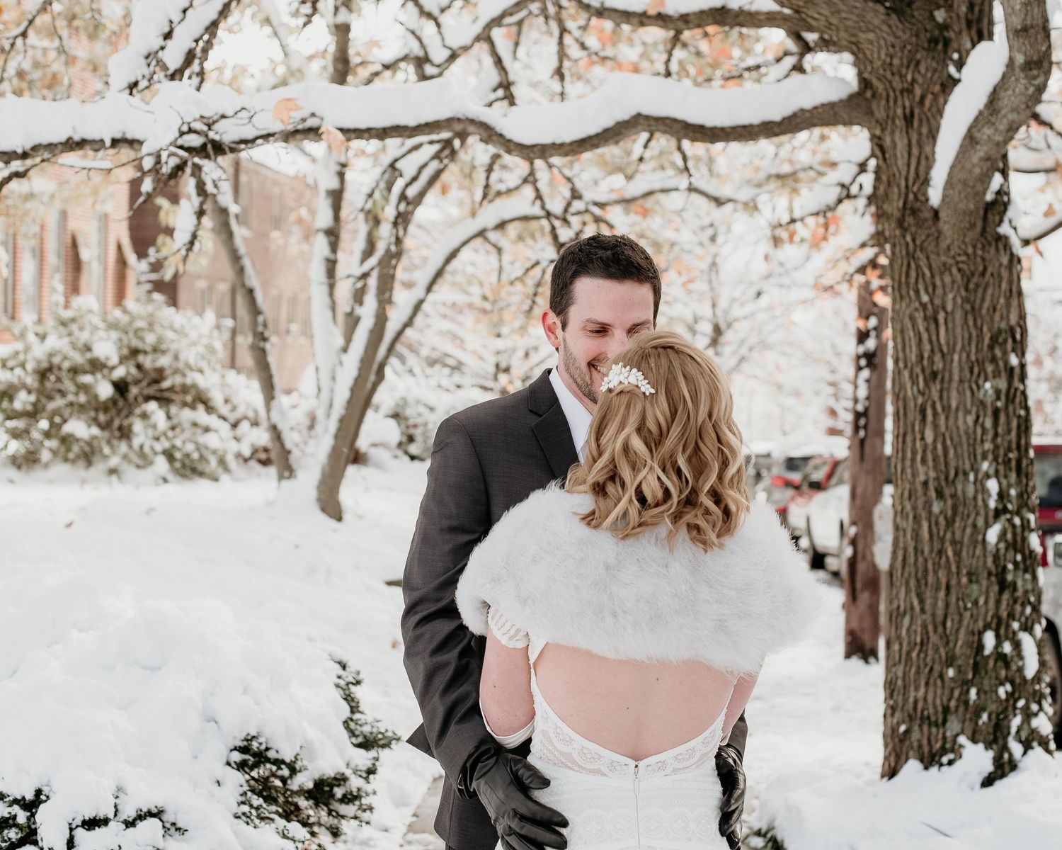 A bride and groom share a romantic kiss outdoors in a snowy winter wonderland wedding setting.