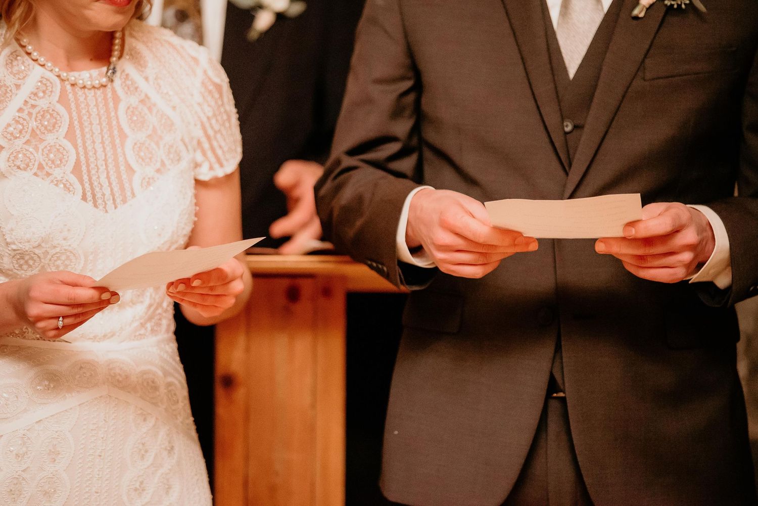 Bride and groom exchanging written wedding vows at altar during ceremony.