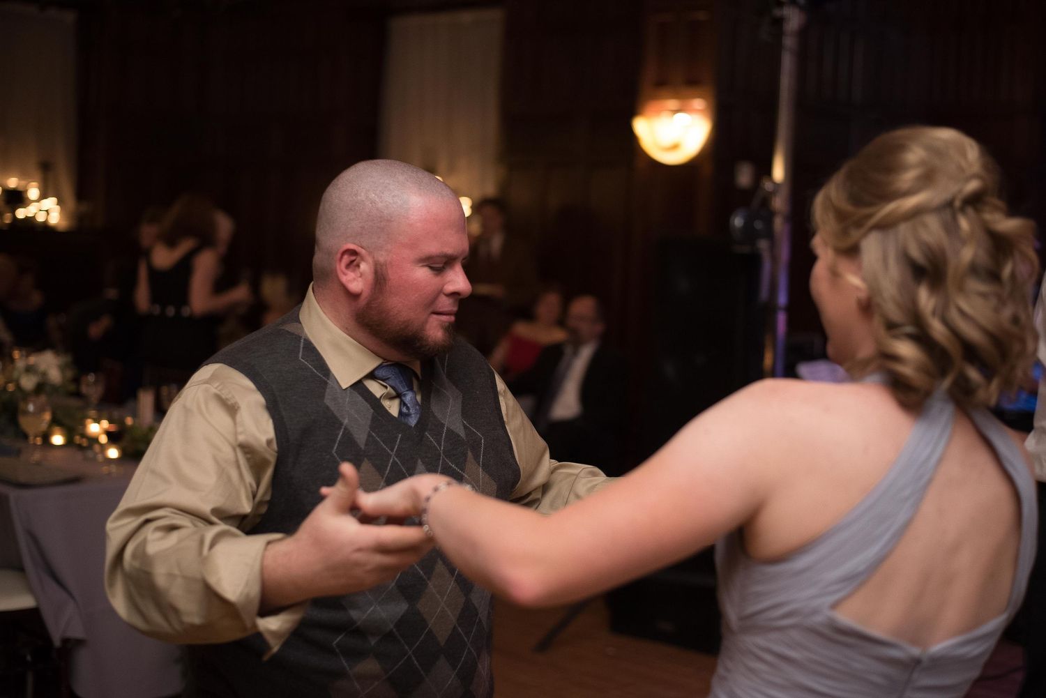 Couple sharing a dance at a wedding reception in a dimly lit ballroom.
